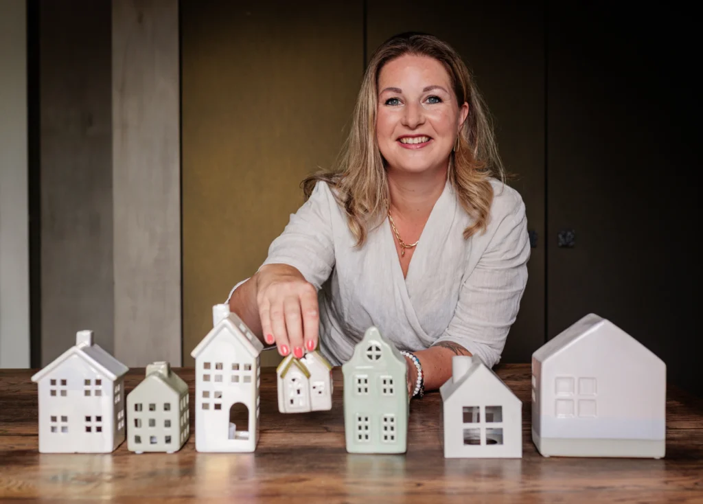 Madeleine Castenmiller, Human Design interieuradviseur, met miniatuur huisjes op houten tafel